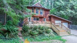 A wooden cabin with a deck, stairs, and a fire pit. - Cedar-sided cabin, RV parking, Kids & Pet friendly (Ashford)