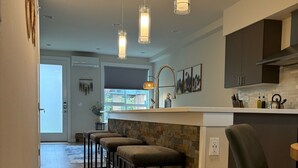 A modern kitchen with a central island, pendant lights, and a bar stool seating area. - Haven at Greenbridge: Near SEA Airport & Downtown Seattle (Seattle)