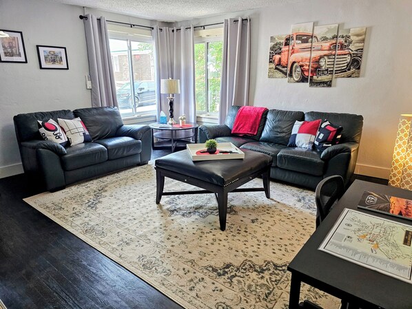 A modern living room with two black leather sofas, a coffee table, and a patterned rug. - Relax At Rt.66 Military Family Favorite (Waynesville)
