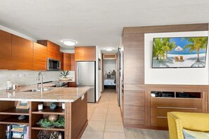 A modern kitchen with wooden cabinets, a built-in microwave, and a large island with a sink.