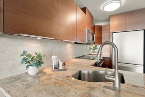 Een moderne keuken met houten kastjes, een roestvrijstalen spoelbak en een inbouwmagnetron.