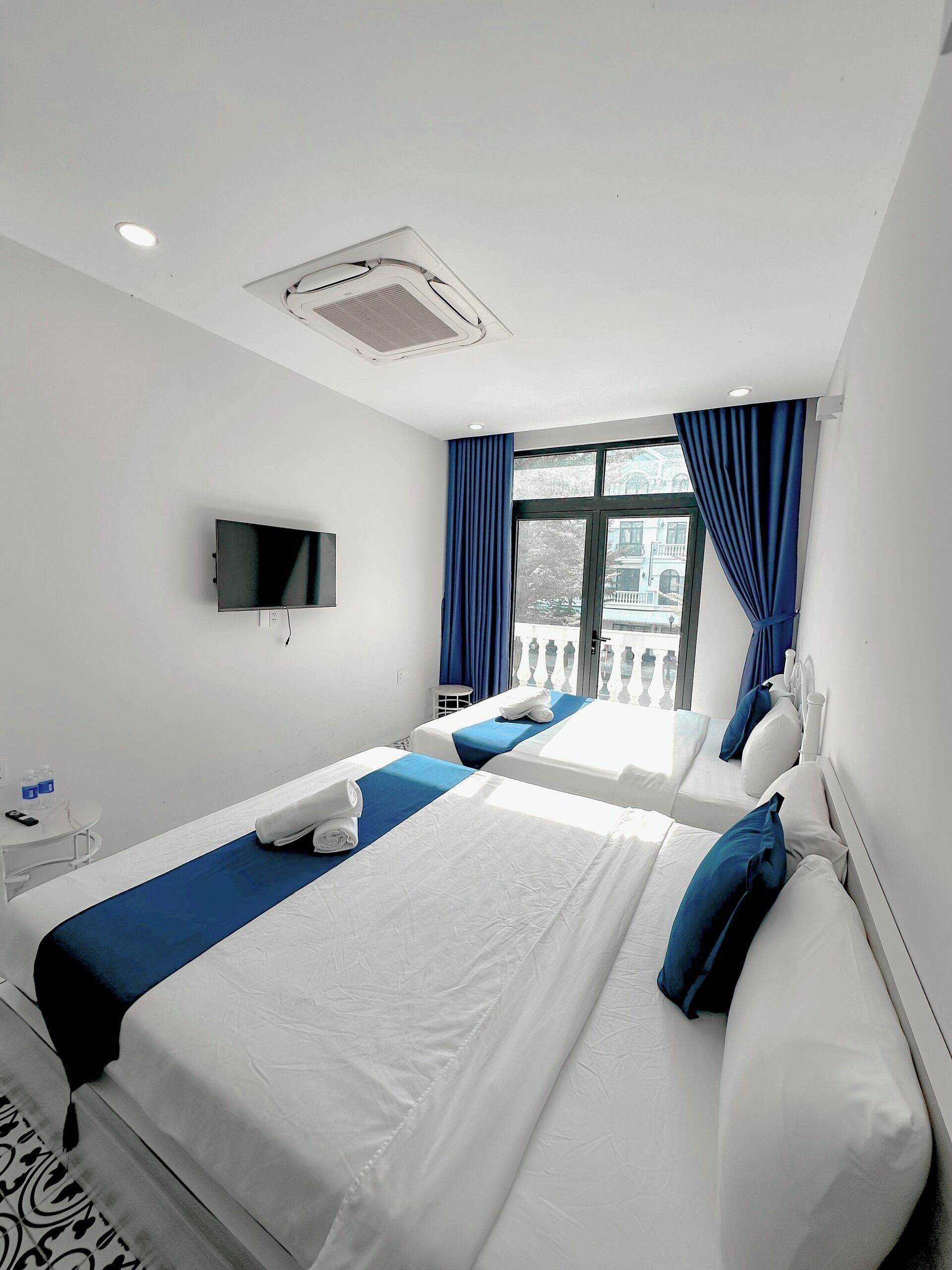 A hotel room with two beds, a TV, and a window with curtains.