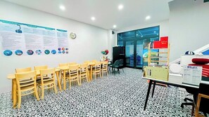 A conference room with a black and white patterned floor, wooden chairs, a table with a whiteboard, and a glass door leading outside. - Lala Boutique Phu Quoc (Phu Quoc)