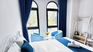 A hotel room with a bed, a small table with chairs, a window with curtains, and a towel rack. - Lala Boutique Phu Quoc (Phu Quoc)