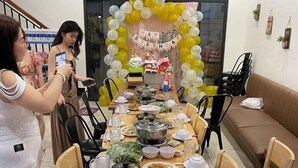 A dining area with a long wooden table set for a meal, surrounded by chairs. A festive balloon arch with a 'Happy Birthday' banner is visible in the background. - Lala Boutique Phu Quoc (Phu Quoc)