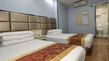 A hotel room with two beds, a mirror, a bathroom, and a wooden floor.