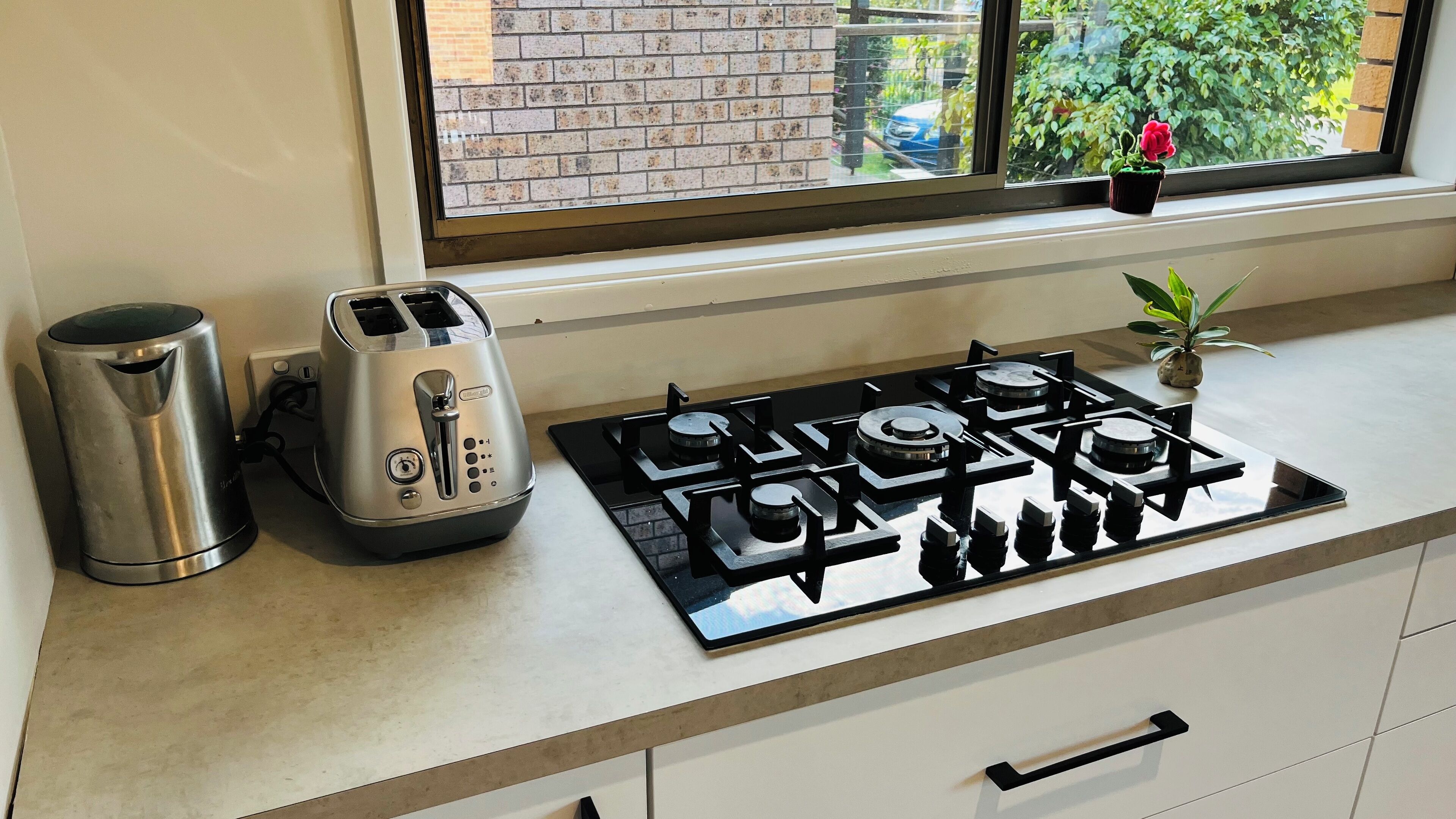 Una cocina con estufa a gas, tostadora y hervidor sobre la encimera.