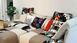 Een moderne woonkamer met een modulaire bank, een potplant en decoratieve wandkunst.
