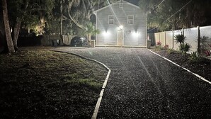 A house with a driveway leading to the front door, surrounded by trees and a fence. - Sun & Speedway Villa - Centrally located to everything. (Daytona Beach)