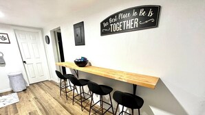 A kitchen with a wooden countertop, black bar stools, and a sign on the wall. - Sun & Speedway Villa - Centrally located to everything. (Daytona Beach)