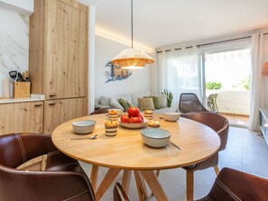 A dining area with a round wooden table, chairs, and a hanging light fixture.