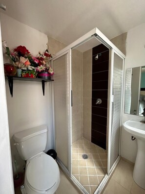A bathroom with a toilet, a shower enclosure, and a sink.