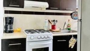 A compact kitchen with dark cabinets, a white stove, and a small countertop.
