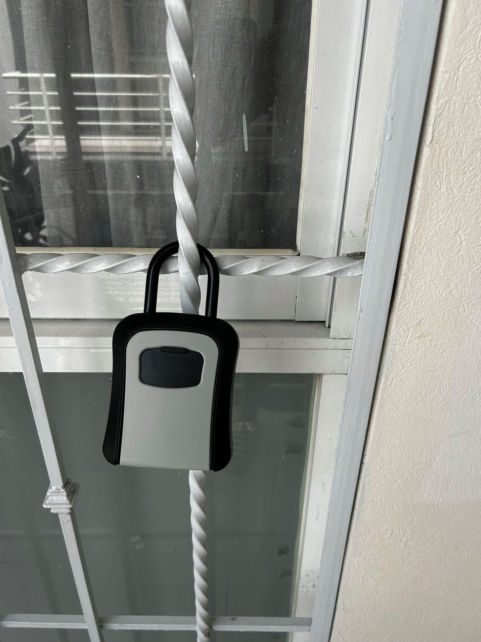 Una ventana con una escalera en espiral de metal y un candado colgando del marco.