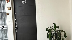 A black door with the number 402, a glass door with a metal handle, and a potted plant on the right.