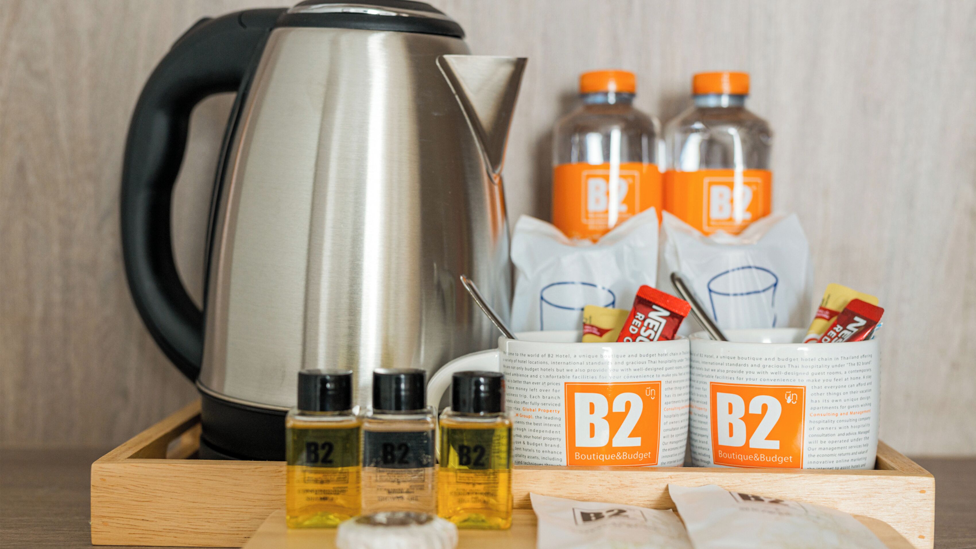 A kitchen setup with a kettle, B2 branded items, and a tray.