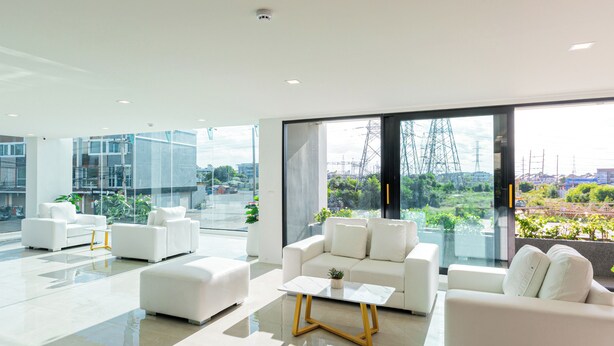 A modern living room with white furniture, large windows, and a view of power lines. - B2 Khon Kaen Wufoo Market Premier Hotel (Khon Kaen)