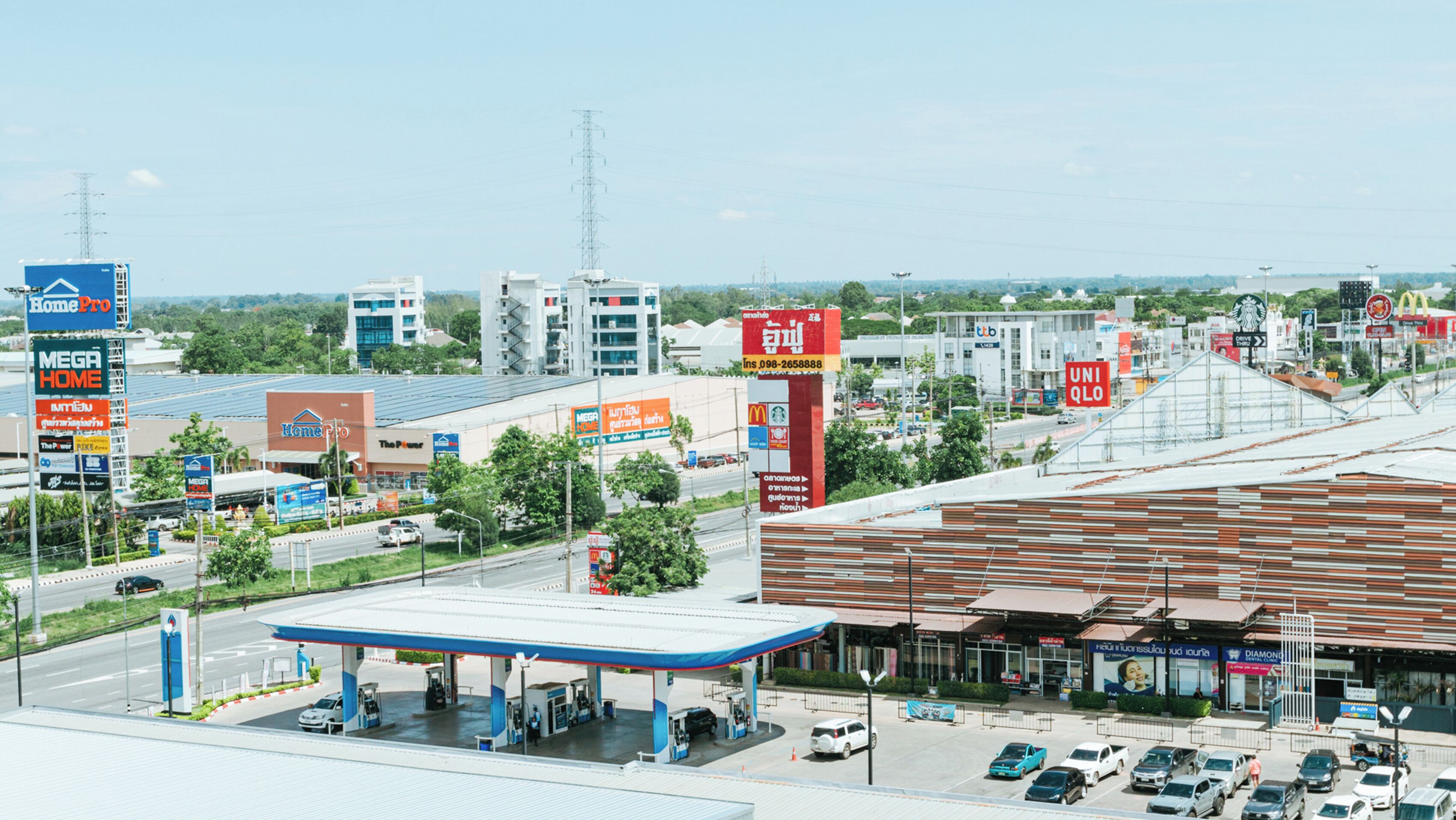 Zona comercial con una estación de servicio, varias tiendas y un edificio grande con letreros.
