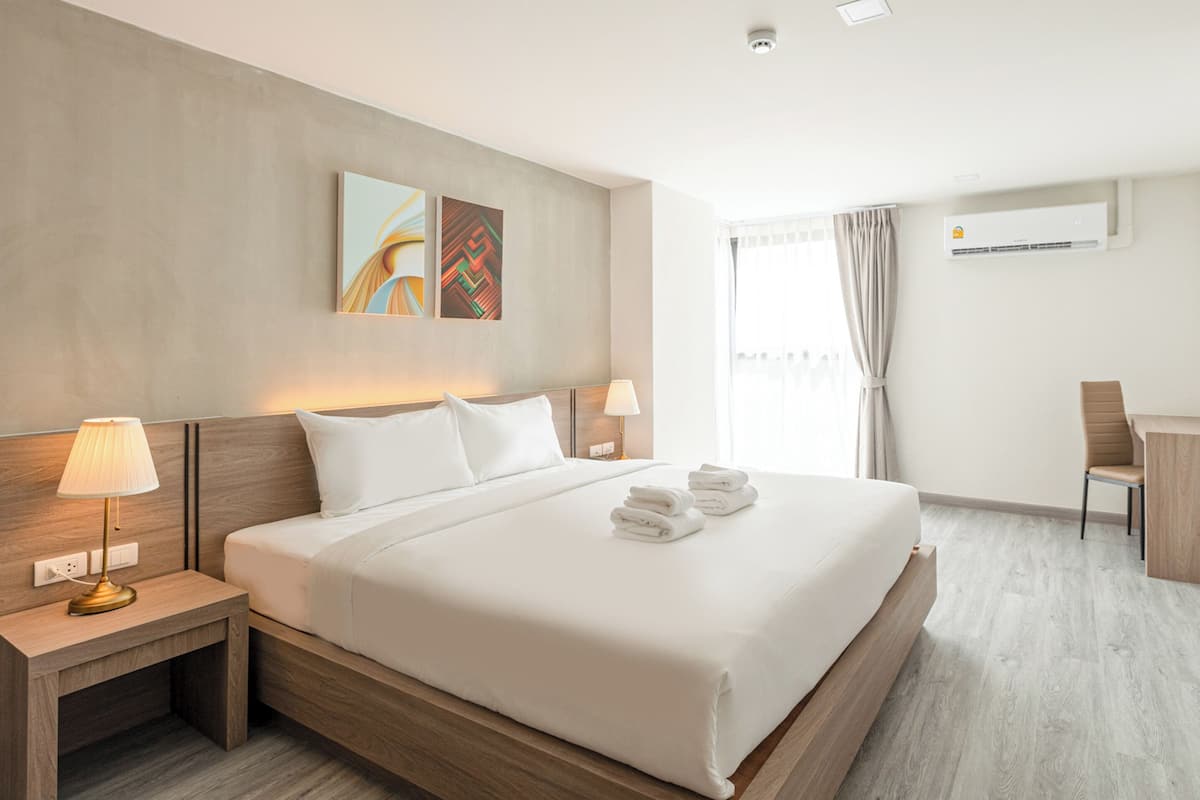 A modern hotel room with a large bed, bedside lamps, a desk, and a television.