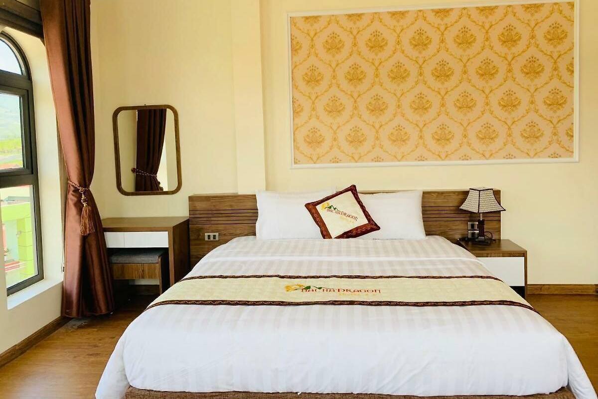 A hotel room with a large bed, a desk, a chair, a mirror, and a window with curtains.