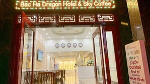 The Bac Ha Dragon Hotel & Sky Coffee entrance with a sign listing services like coffee, cocktails, smoothies, and fruit juice. - Bac Ha Hotel Lao Cai- by Bay Luxury (Bac Ha)