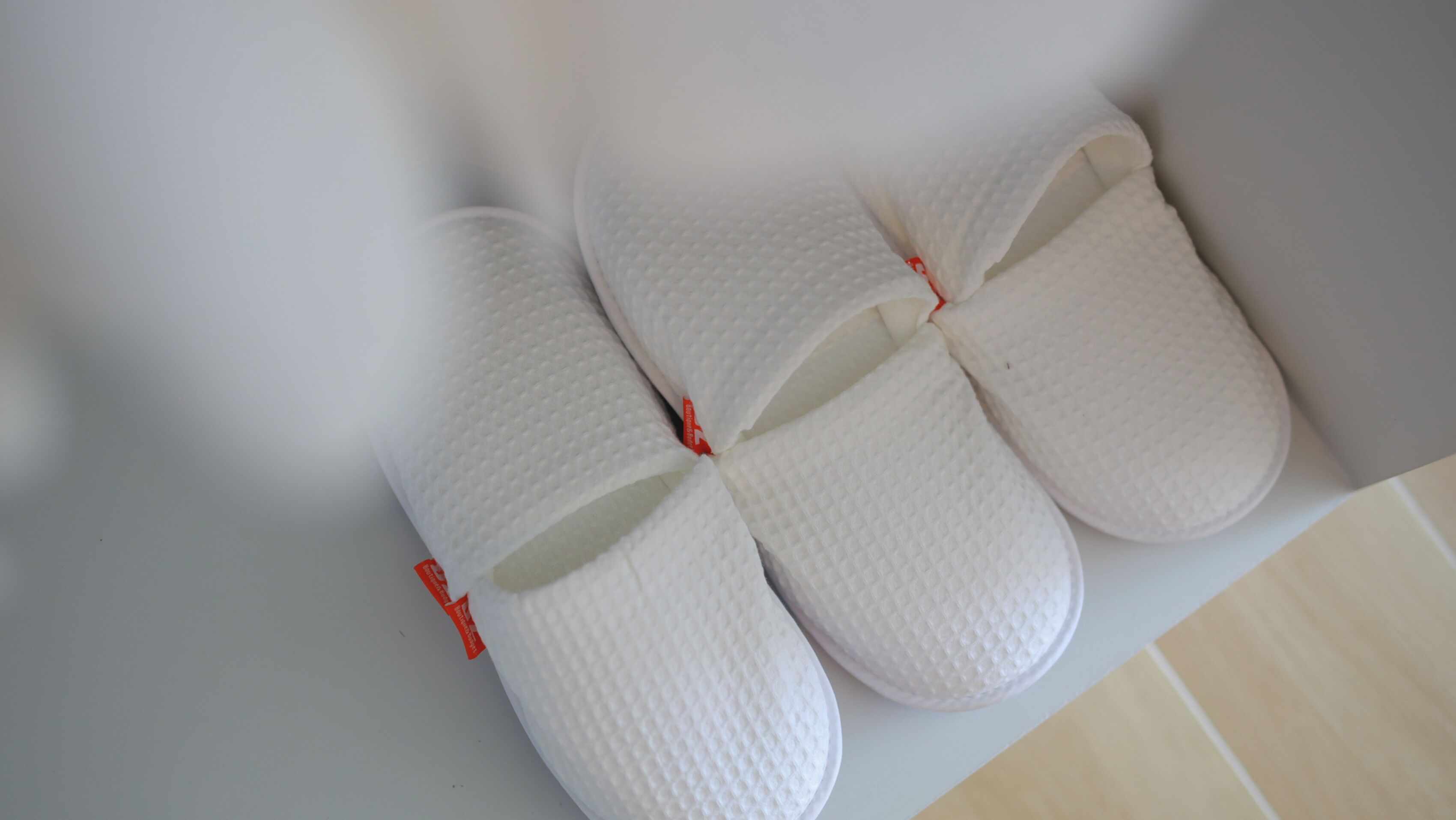 A pair of white slippers with red accents on a white surface.