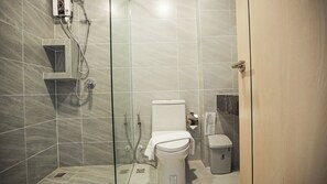 Ein modernes Badezimmer mit Duschkabine aus Glas, Toilette und Mülleimer.