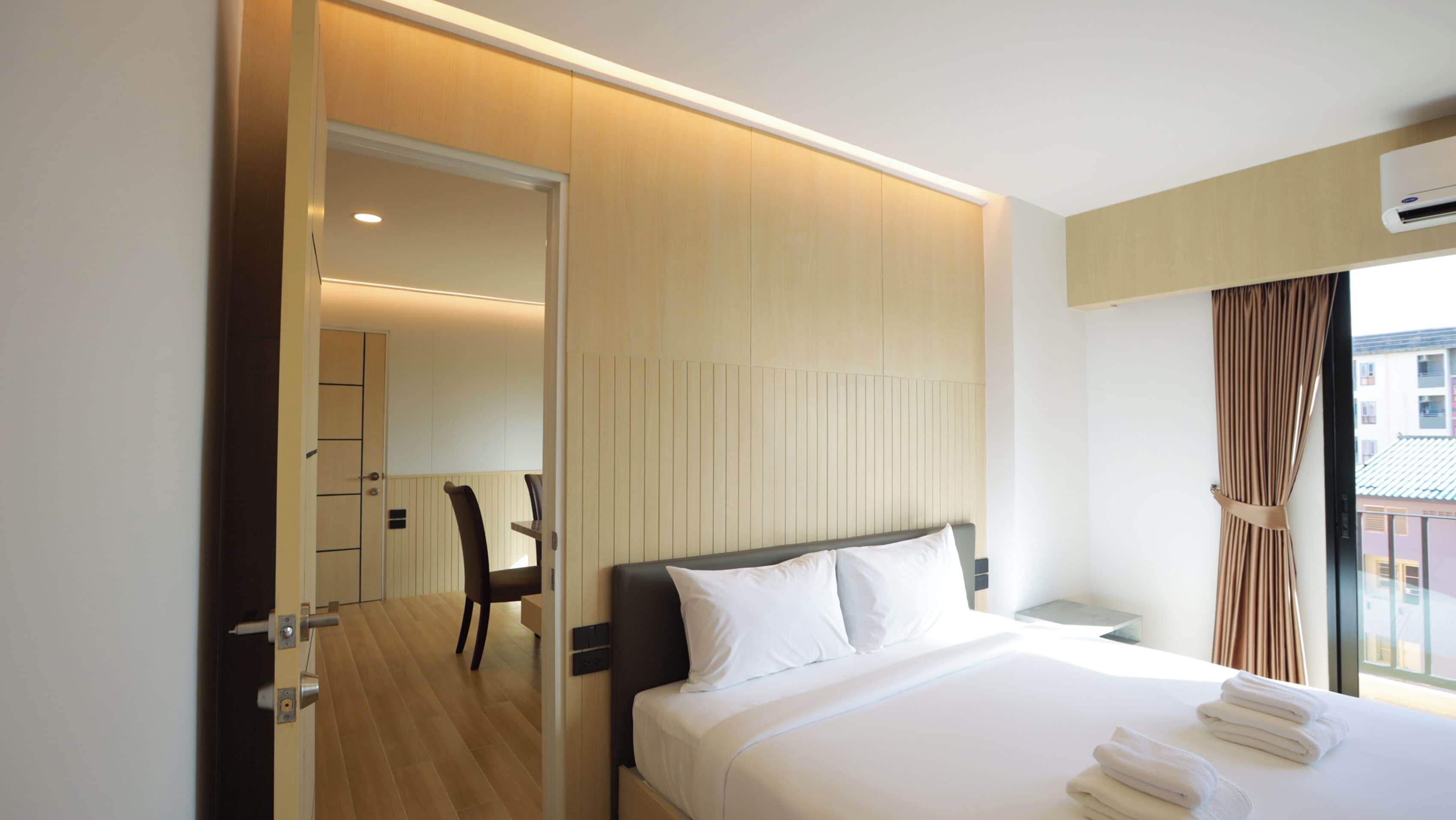 Een hotelkamer met een bed, een stoel, een bureau en een raam met gordijnen.