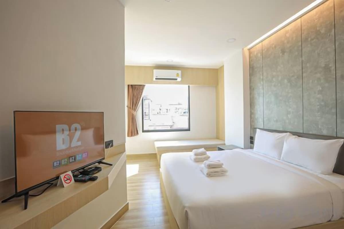 A hotel room with a large bed, a television, and a window with curtains.