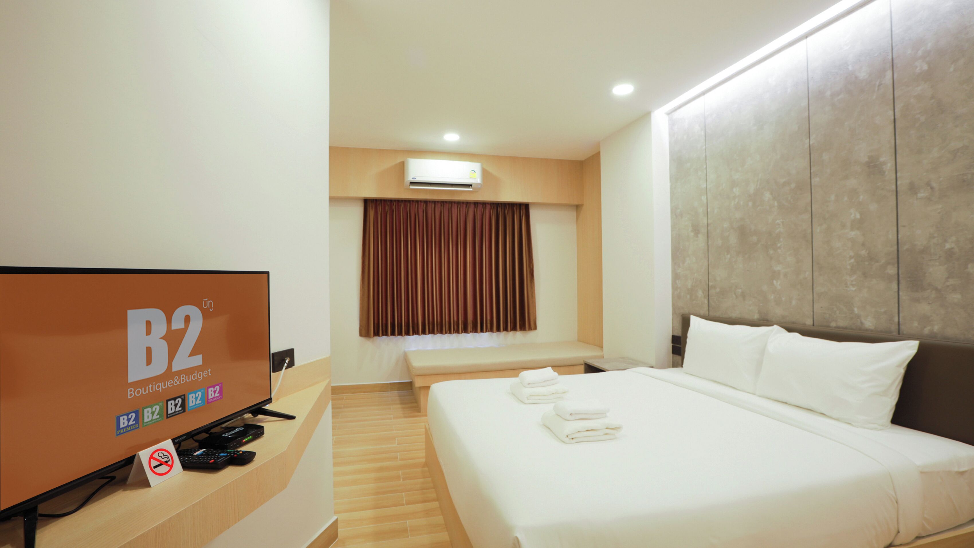 Una habitación de hotel con una cama grande, un escritorio con televisor y una ventana con cortinas.