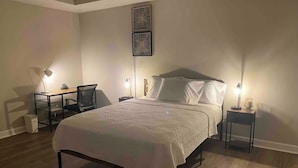 Une chambre à coucher comprenant un lit, deux tables de chevet, un bureau et deux chaises.