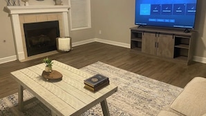 Un salon avec une cheminée, un téléviseur, une table basse et un canapé.