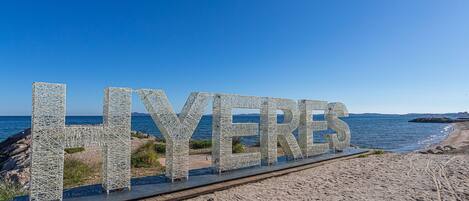 A beach with the word "LYERES" spelled out in large letters on a boardwalk.