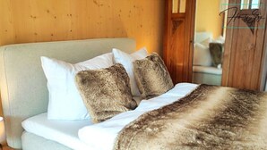 Un lit avec des oreillers blancs et bruns, une tête de lit en bois et une couverture de couleur claire.