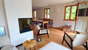 Un salon moderne doté d’une cheminée, de planchers en bois et d’un coin repas avec une table et des chaises.