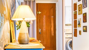 Un couloir avec un meuble bleu, une porte en bois et un lave-linge.
