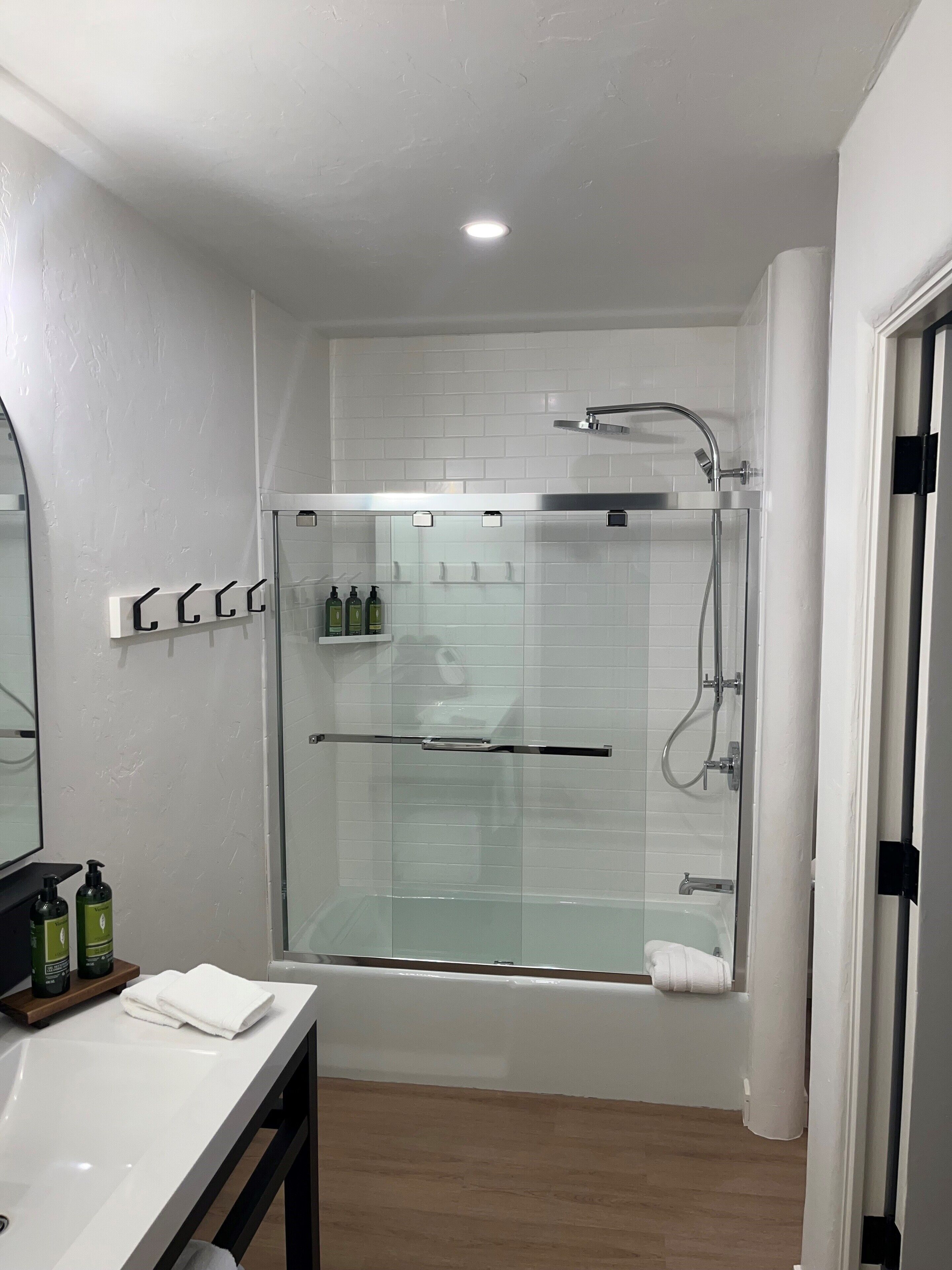 A modern bathroom with a glass-enclosed shower, a white sink, and a mirror.