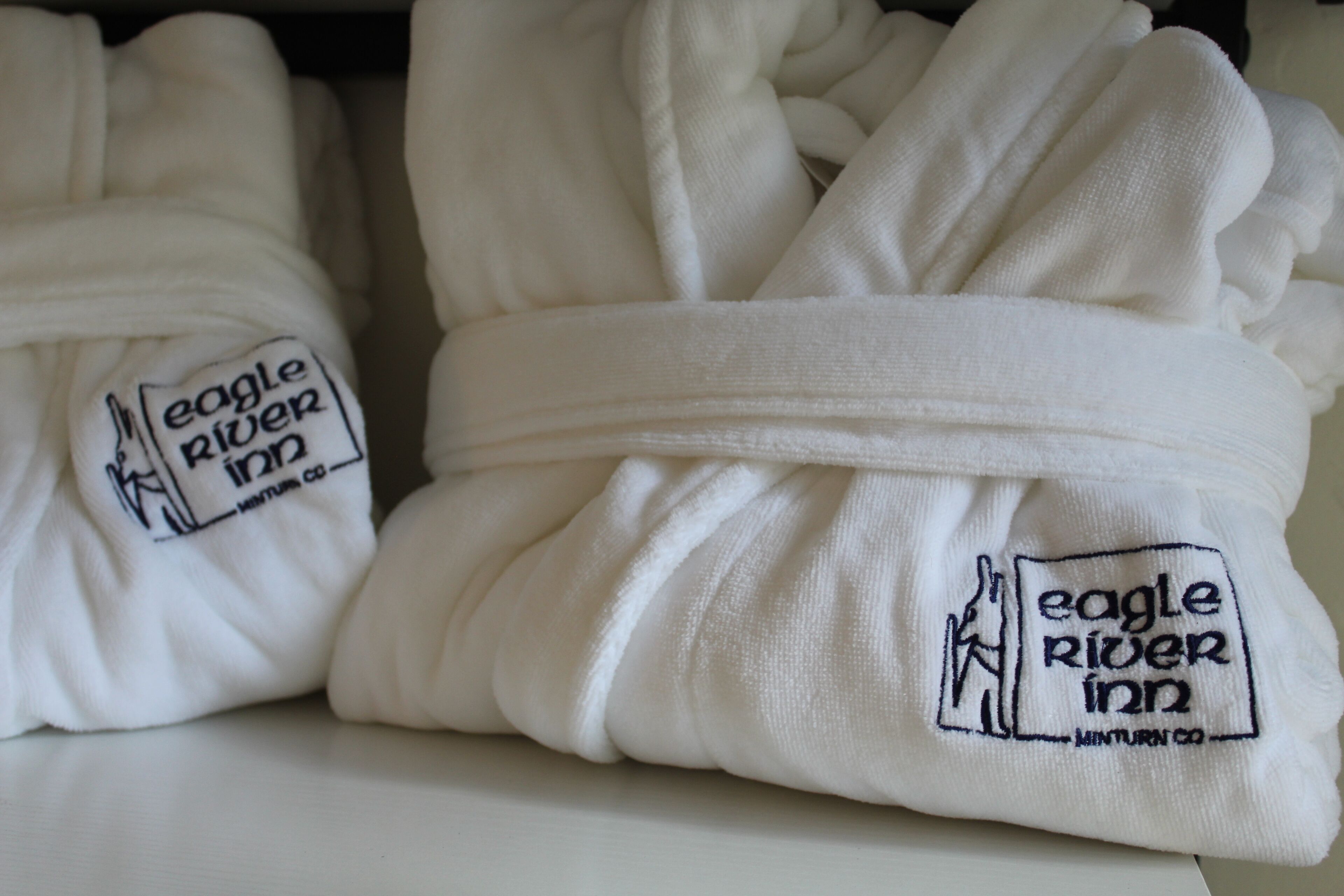 Neatly folded white towels with embroidered logos of Eagle River Inn and Minturn Co.