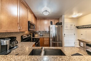 A kitchen with wooden cabinets, stainless steel appliances, granite countertops, and a stainless steel refrigerator.