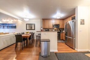 Una cocina moderna con armarios de madera, electrodomésticos de acero inoxidable y un comedor con sofá y sillas.
