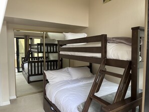 Una habitación con literas, una puerta corredera que da a un espacio exterior y suelo alfombrado.