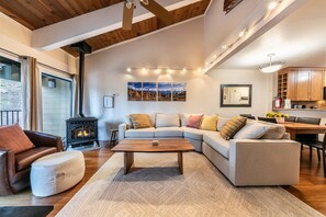 A cozy living room with a sectional sofa, a coffee table, and a fireplace.