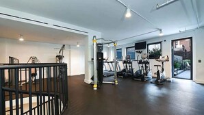 Un gimnasio con cintas de correr, elípticas y una máquina de pesas.
