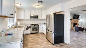 A modern kitchen with white cabinets, stainless steel appliances, and a wooden floor. - Peaceful & Modern Ridgecrest Retreat: Spacious 4-Bed Home w/ Private Yard (Ridgecrest)