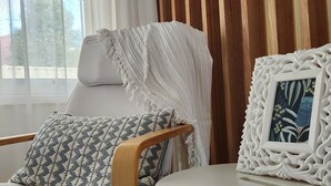 A room with a wooden chair, a white table, and a framed picture.