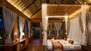 A room with a bed, curtains, a bedside table, and a lamp. - Villa Sujati (Ubud)