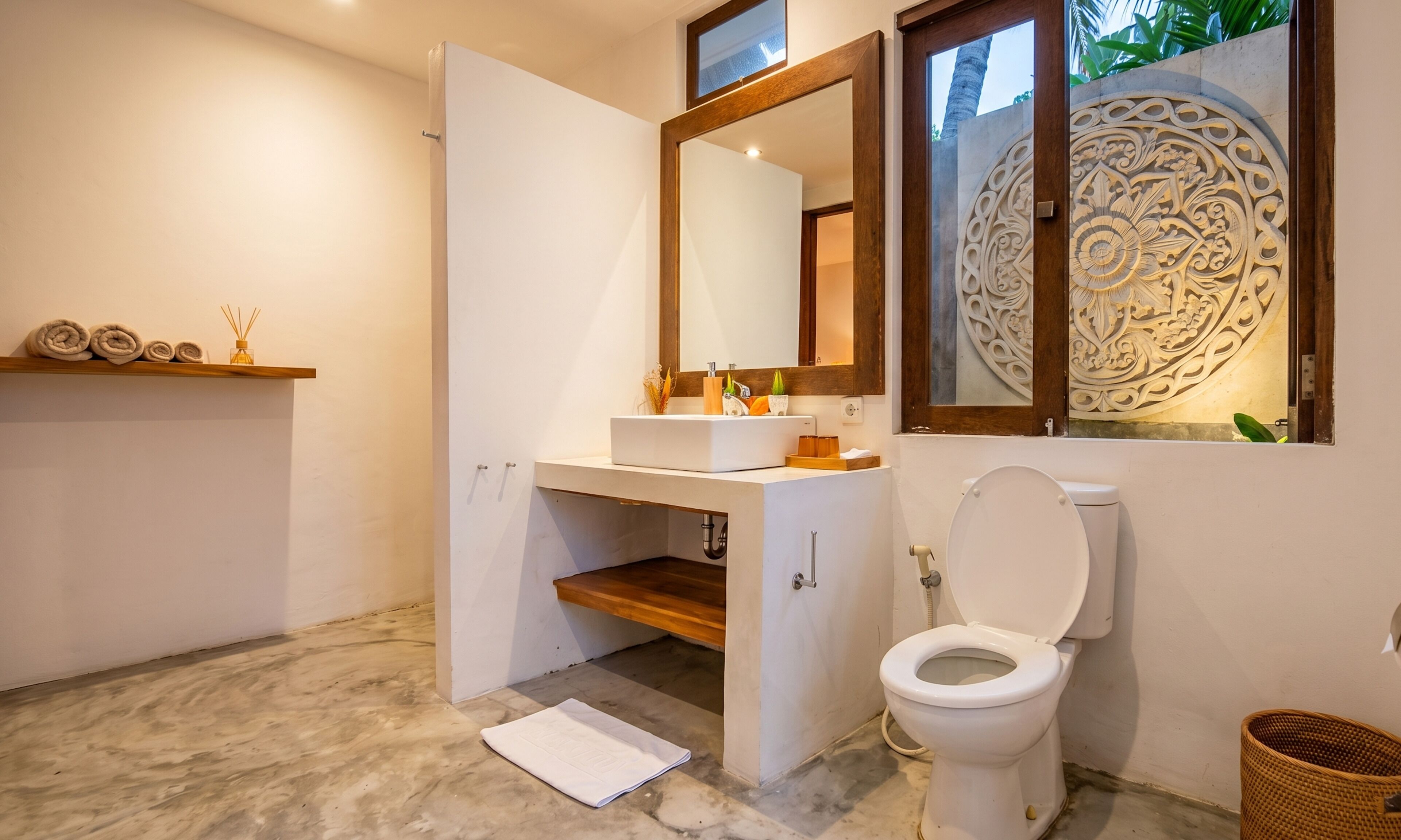 A modern bathroom with a white sink, mirror, and toilet.