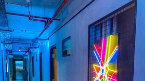 Un pasillo con una instalación artística de neón en la pared y un techo iluminado en azul.