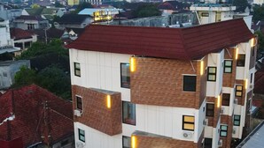Un edificio de varios pisos con techo rojo, paredes blancas y numerosas ventanas iluminadas.