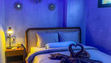 A bedroom with a bed, a nightstand, decorative wall art, and a wall-mounted TV.